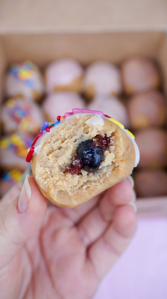 Blueberry filled Raw Bite with a box full of bites in the background